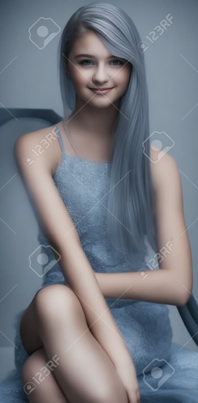 Подросток девочка сидит в сером платье