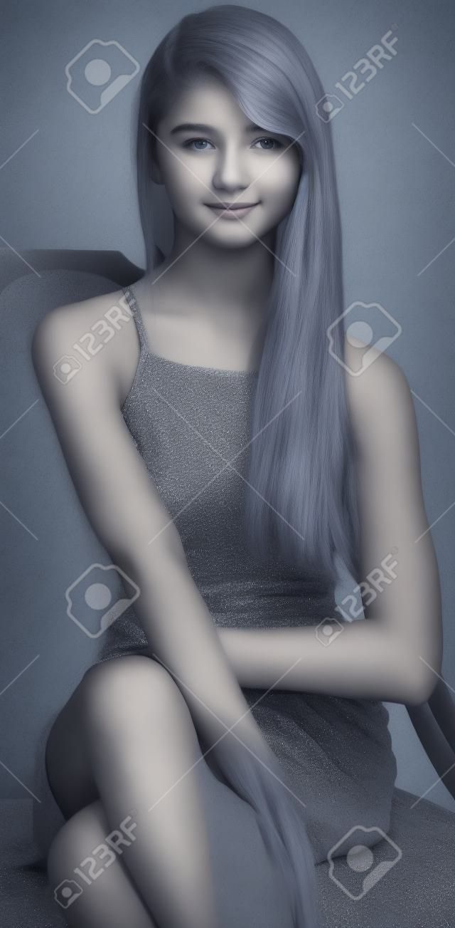 Muchacha adolescente que se sienta en un vestido gris