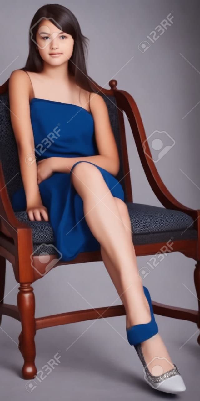 Muchacha adolescente que se sienta en una falda y tacones