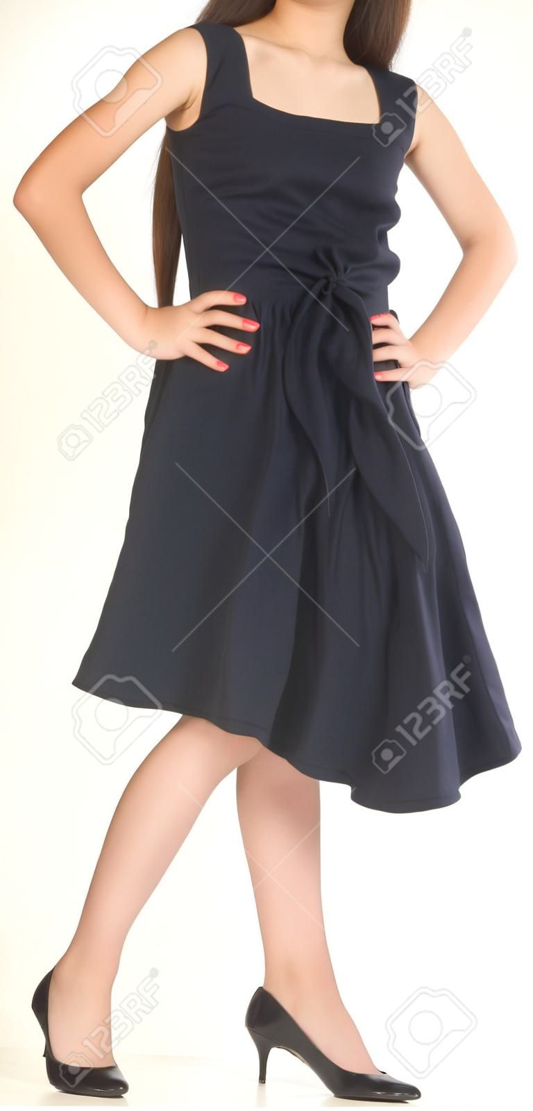 Adolescente de la muchacha asiática posando en un vestido negro y zapatos de tacón