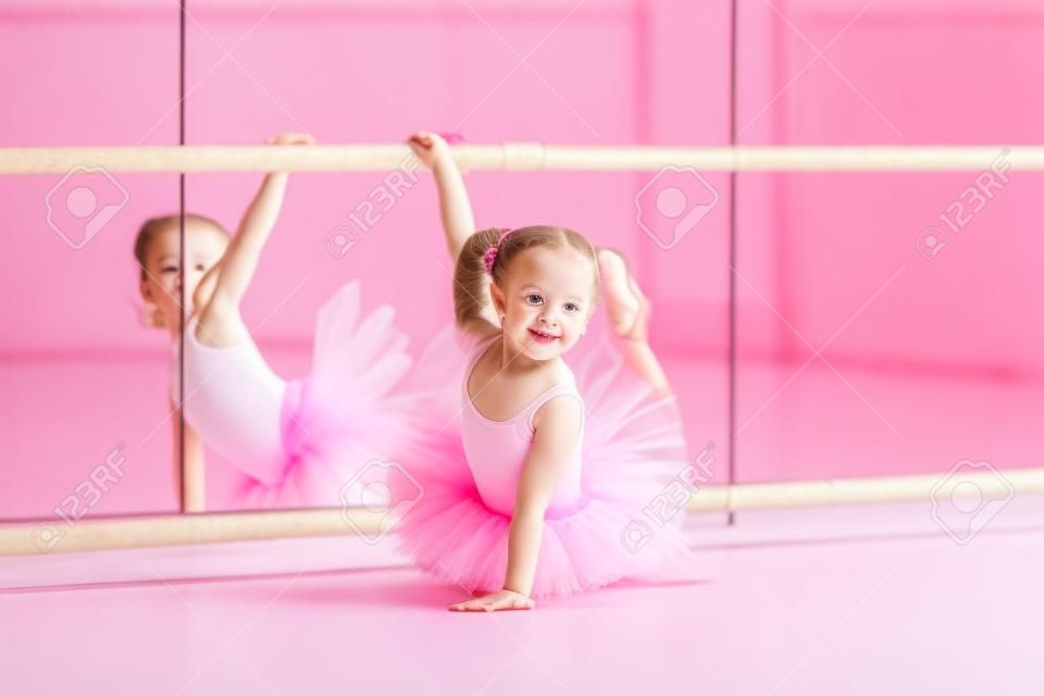 Menina pequena da bailarina em um tutu cor-de-rosa. Adorável criança dança balé clássico em um estúdio branco. Crianças dançam. Crianças realizando. Jovem dançarino talentoso em uma classe. Criança pré-escolar tendo aulas de arte.
