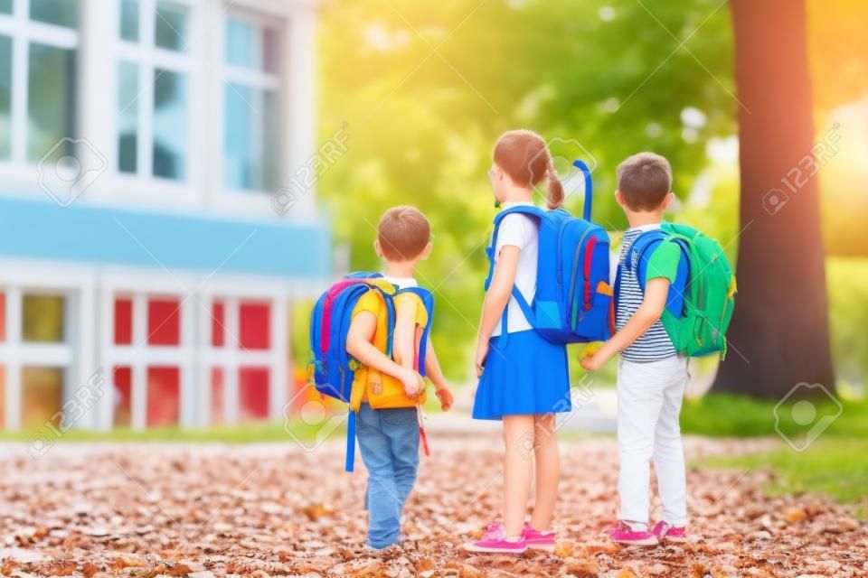 Kinder gehen wieder zur Schule. Beginn des neuen Schuljahres nach den Sommerferien. Junge und Mädchen mit Rucksack und Büchern am ersten Schultag. Beginn des Unterrichts. Bildung für Kindergarten- und Vorschulkinder.