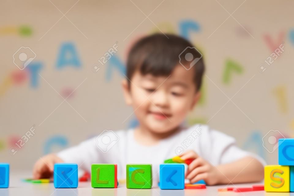 Dziecko uczy się liter i cyfr. Dzieciak z kolorowymi drewnianymi klockami abc. Mały chłopiec pisowni słów z edukacyjnymi zabawkami klockowymi. Dzieci odrabiania lekcji w szkole na białym biurku. Sypialnia dla dzieci w wieku przedszkolnym