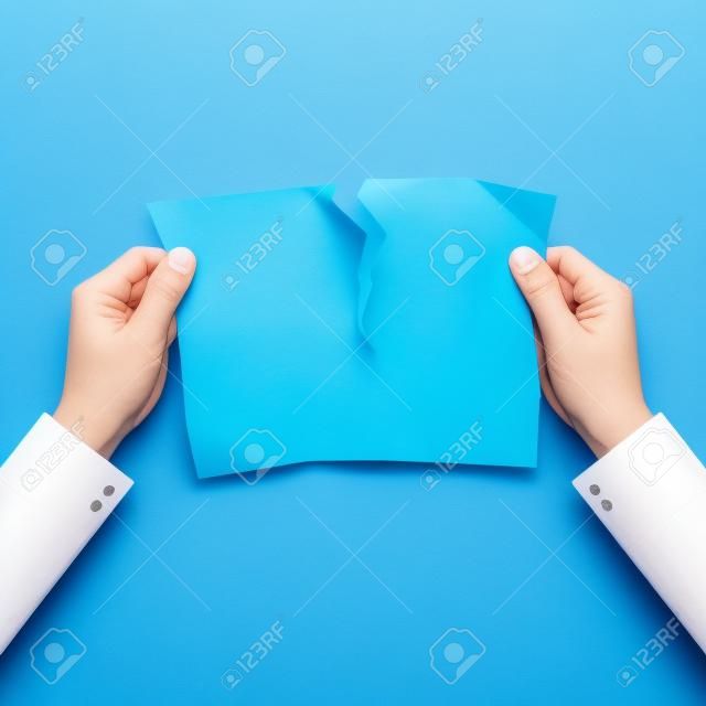 파란색 배경에 종이를 찢는 손