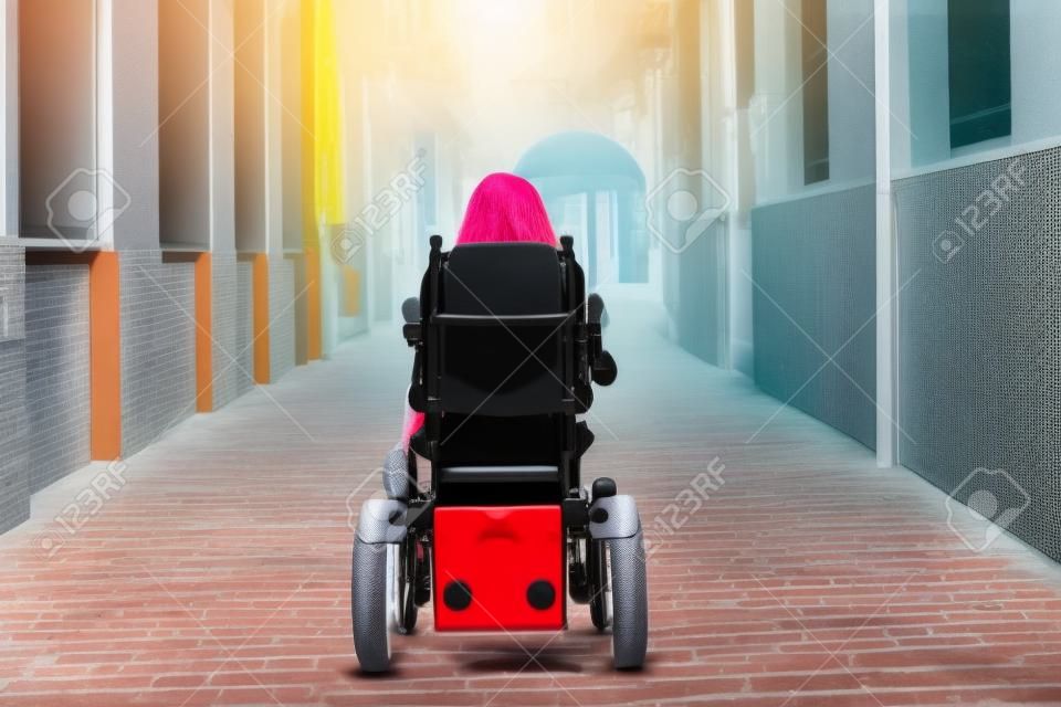 Frau mit Behinderung, eingeschränkter Mobilität und kleiner Statur in einem Elektrorollstuhl, die von hinten durch die Innenstadt geht, Konzept Behinderung, Behinderung, Behinderung, besondere Bedürfnisse