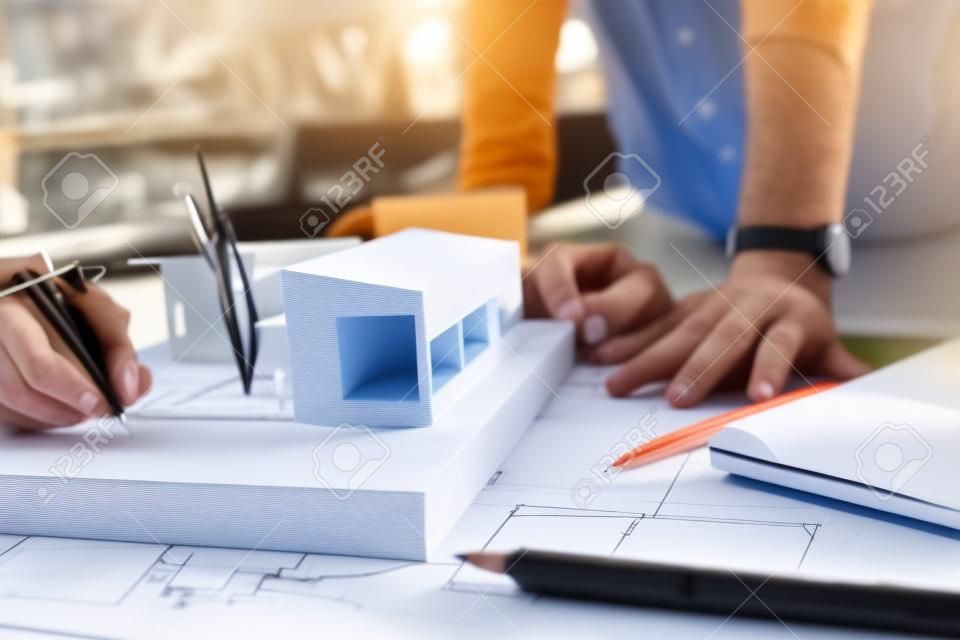 Closeup Bild von gestressten Architekten Denken und Zeichnen von Zeichnung Papier Stil mit Architekturmodell und Laptop auf Tisch , wie scheitern