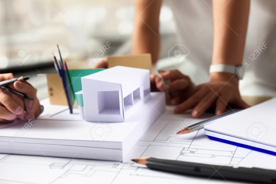Closeup Bild von gestressten Architekten Denken und Zeichnen von Zeichnung Papier Stil mit Architekturmodell und Laptop auf Tisch , wie scheitern
