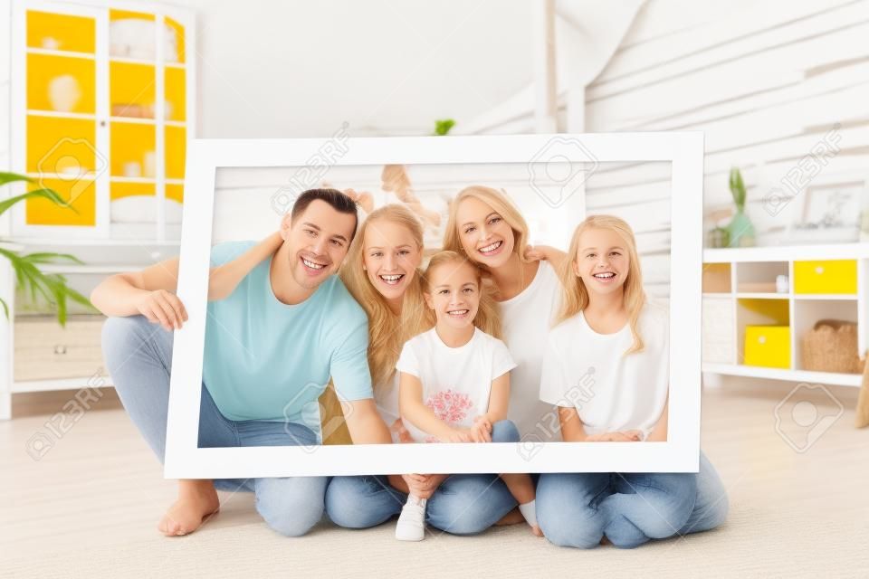 Grote gelukkige familie houden fotolijst en glimlachen. de hele familie draagt witte en gele t-shirts.