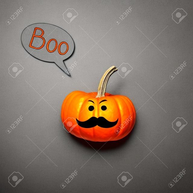 Halloween pompoen Jack o Lantaarn met snor en spraakbel op grijze achtergrond.