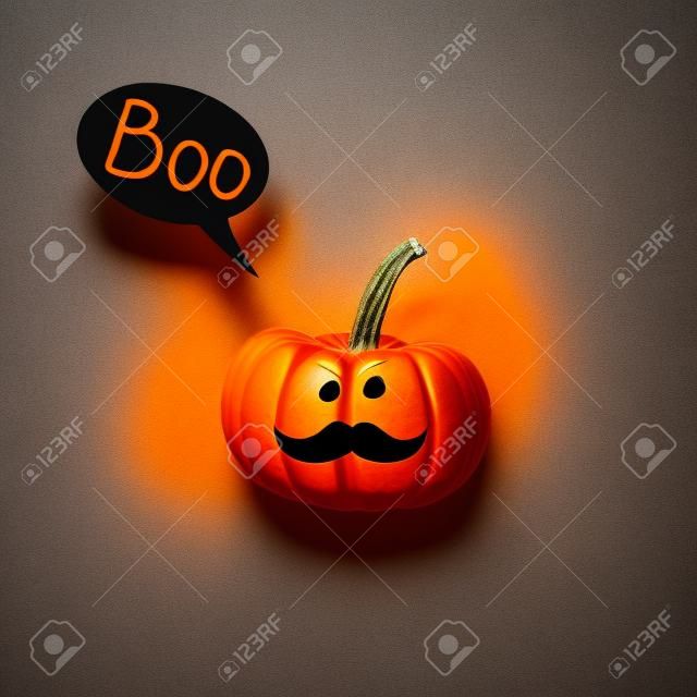Halloween pumpkin Jack o Lantern with mustache and speech bubble on gray background.