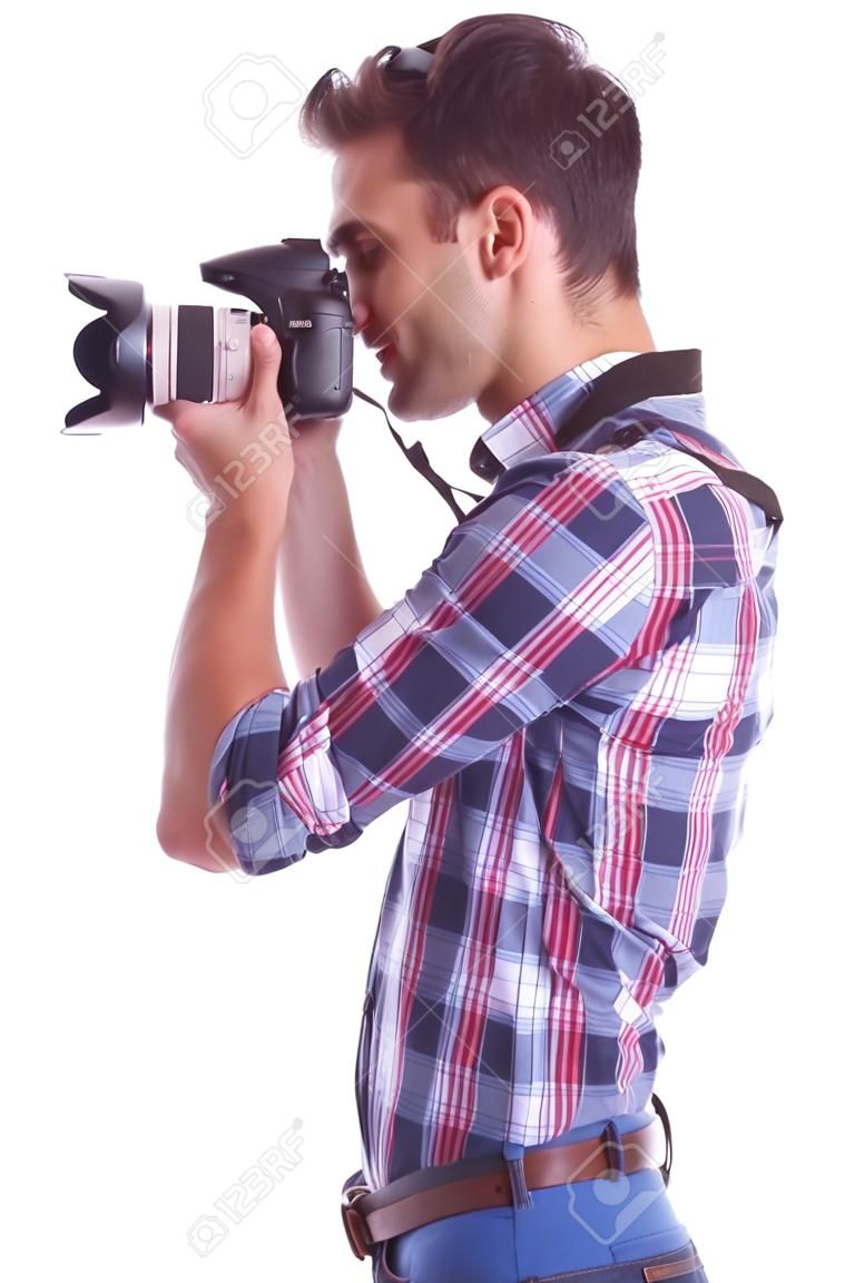 Vista lateral de un joven fotógrafo toma una foto. Aislados en blanco
