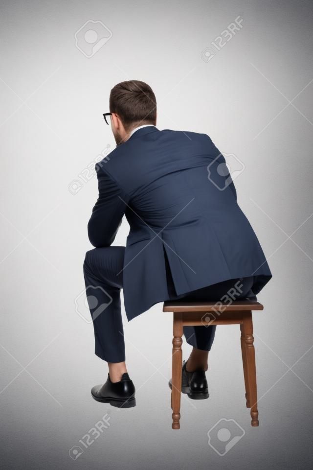 一个坐在白色背景椅子上的年轻商人的背影