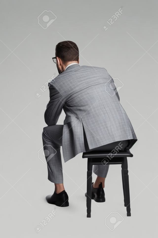 一個年輕的商人坐在椅子上的後視圖。在白色背景上
