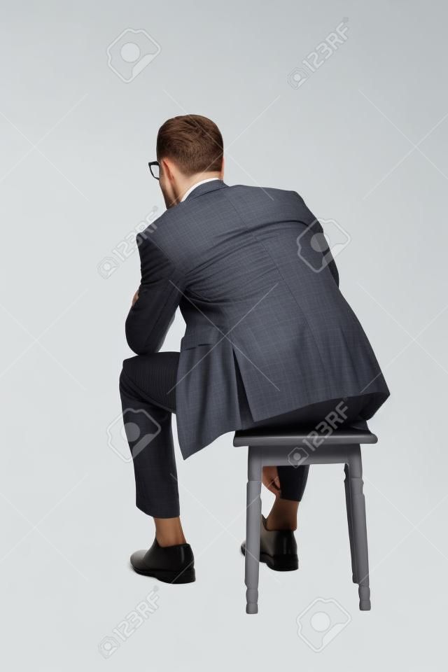一個年輕的商人坐在椅子上的後視圖。在白色背景上