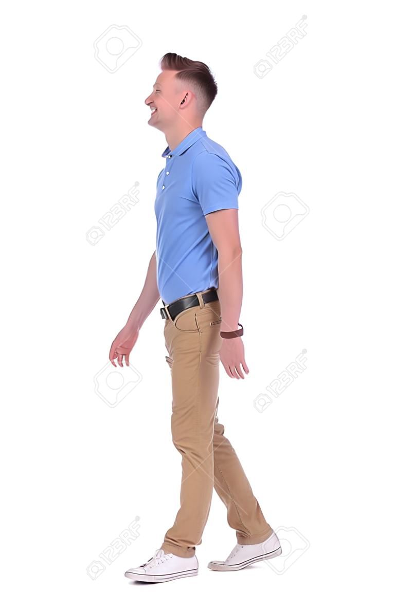 젊은 캐주얼 남자의 전체 길이 측면보기 사진 앞으로 걷고 웃는 동안 카메라에서 멀리 찾고. 흰색 배경에 고립