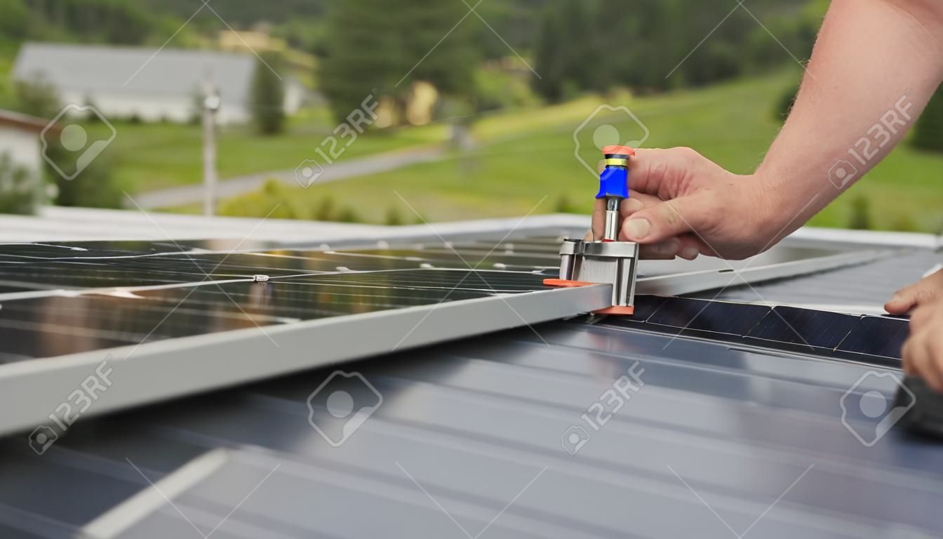 Mounting solar panel, installing solar panels on the roof of the house. Connection of solar panels. Close up of worker installing and working on maintenance of photovoltaic panel system installed.