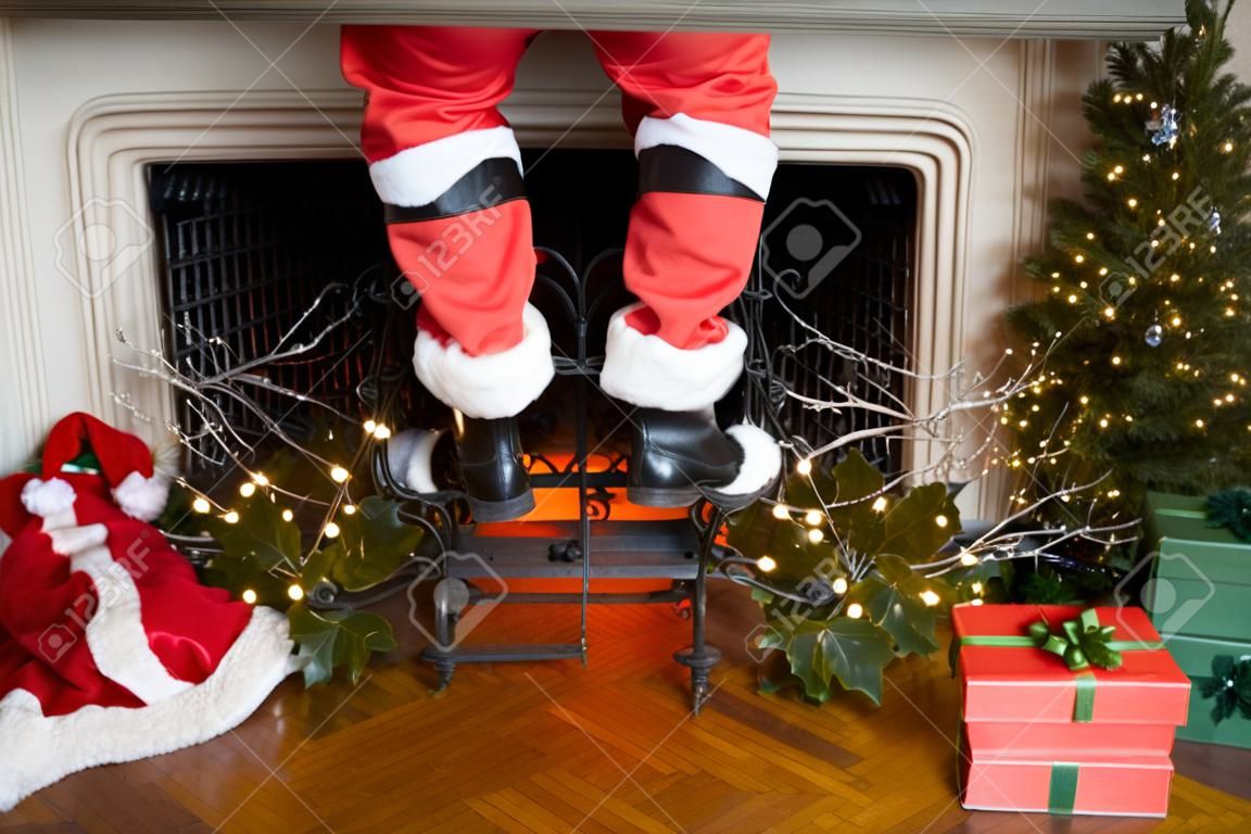 Kerstman's broek en laarzen komen door de schoorsteen met kerstversieringen rond