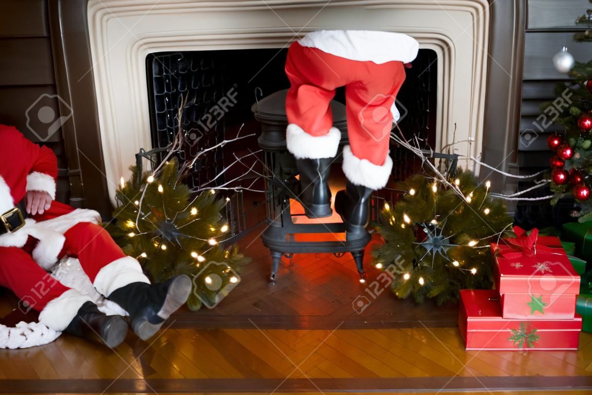 Babbo pantaloni e stivali venuta giù il camino con decorazioni di Natale intorno