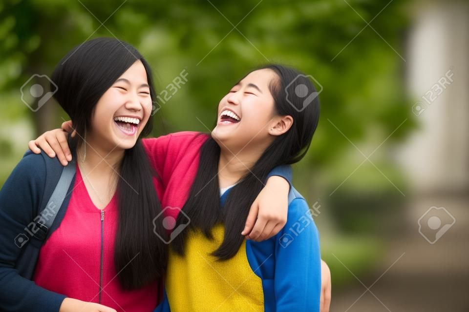 Ein Porträt von glücklichen zwei jungen asiatischen Studenten lachen, scherzen um zusammen
