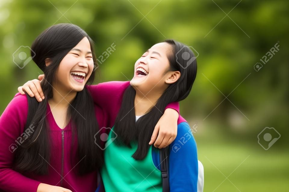 Un portrait de deux jeunes heureux étudiants asiatiques rire, plaisanter ensemble