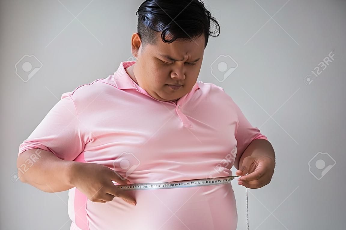 Young fat man measure his belly