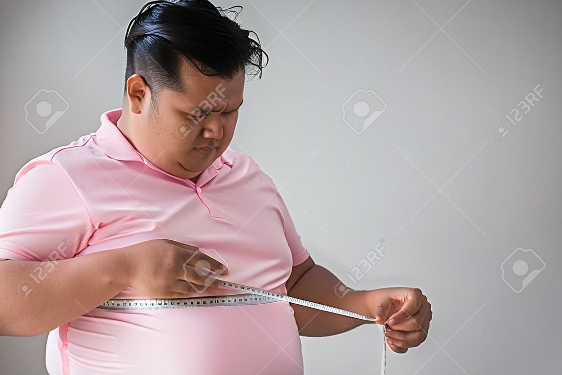 Young fat man measure his belly