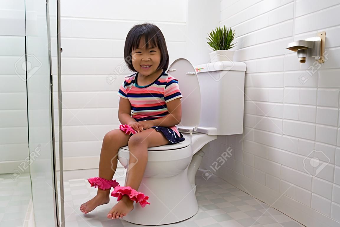 앉아서 변기 사용법을 배우는 아이