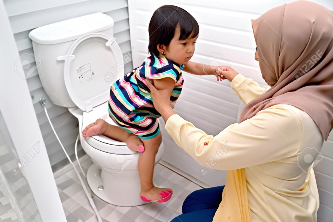 moslim moeder helpen haar kind om toilet te gebruiken
