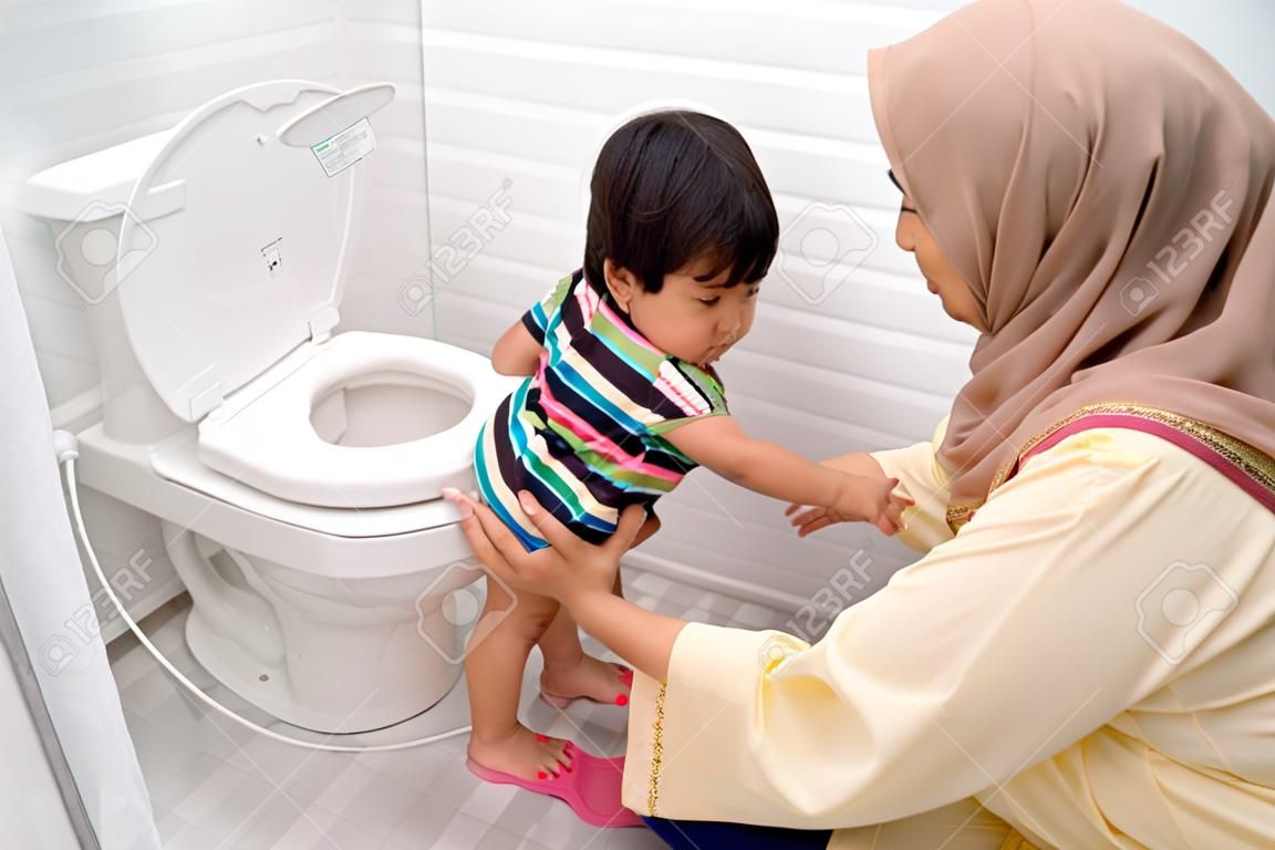 moslim moeder helpen haar kind om toilet te gebruiken