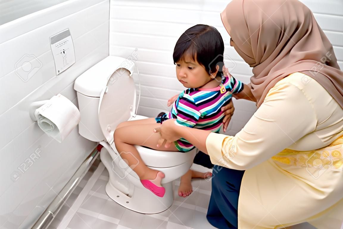 une mère musulmane aide son enfant à utiliser les toilettes