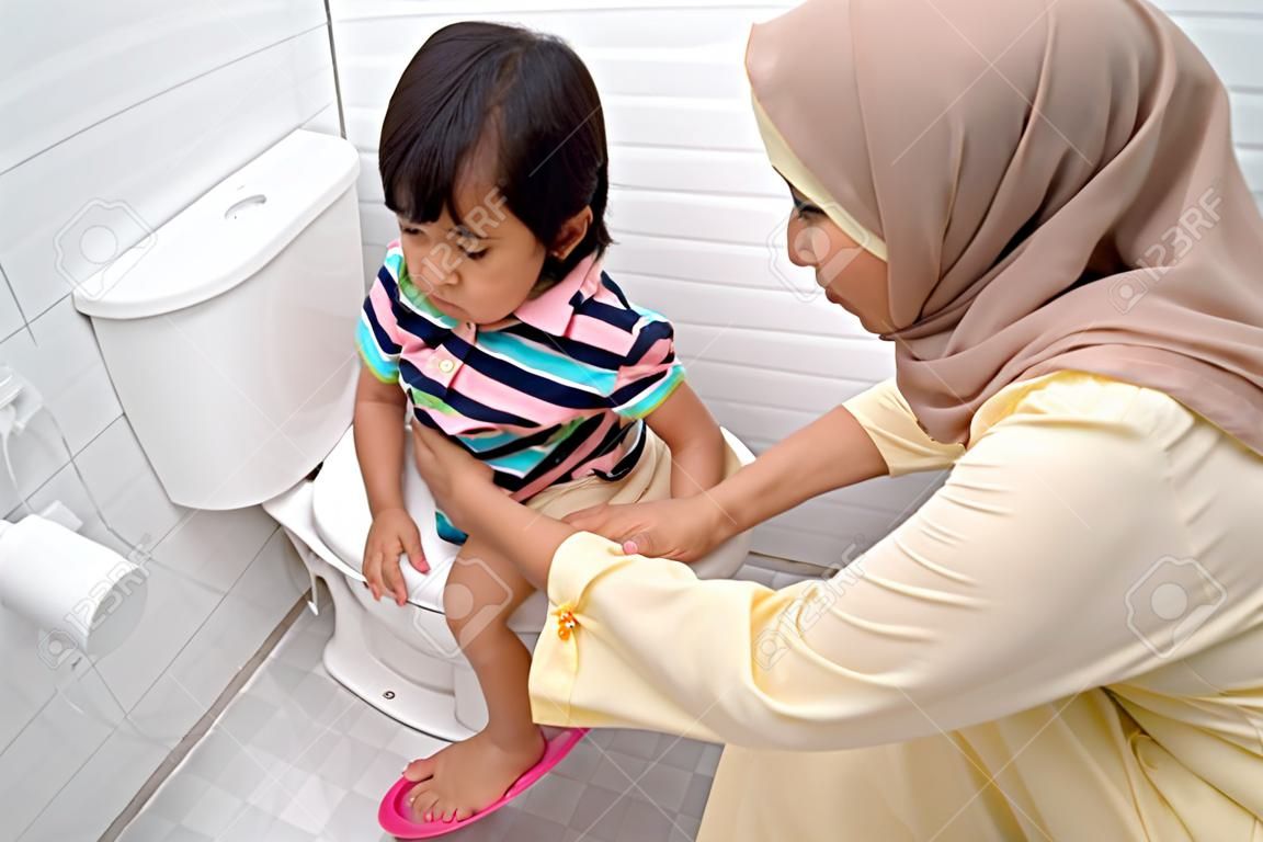muslim mother help her kid to use toilet