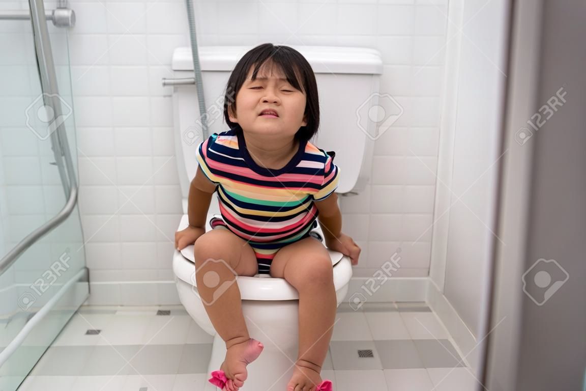 asian kid push it hard while sitting on toilet
