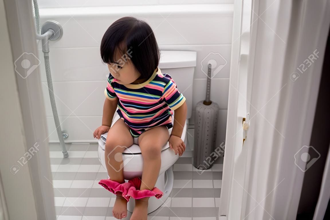 azjatycki maluch siedzący w toalecie z opuszczonymi spodniami