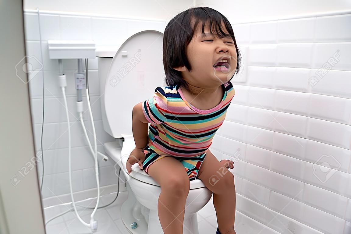 asian kid push it hard while sitting on toilet
