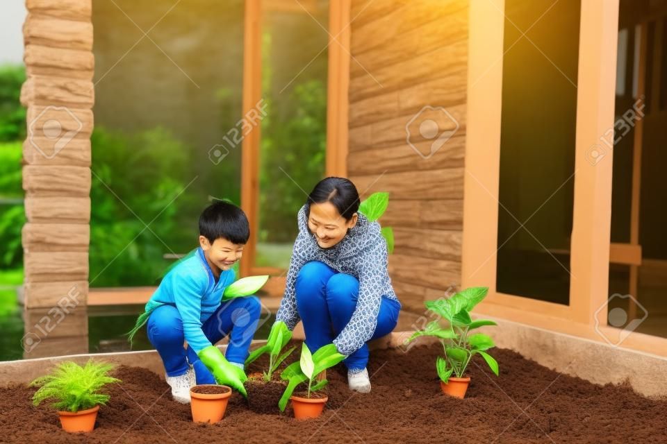 mamma asiatica e suo figlio che piantano una pianta nel giardino di casa