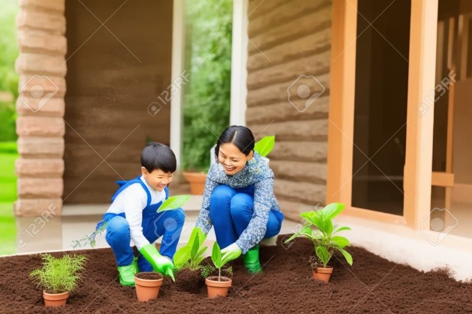 아시아 엄마와 그녀의 아들이 집 정원에 식물을 심다