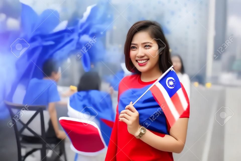 Azjatycka kobieta trzymająca flagę Malezji podczas świętowania dnia niepodległości
