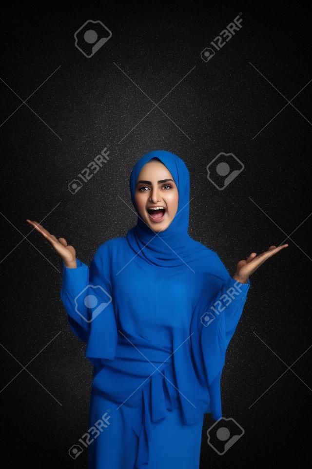 mujer musulmana eufórica levantando el brazo en una foto de estudio