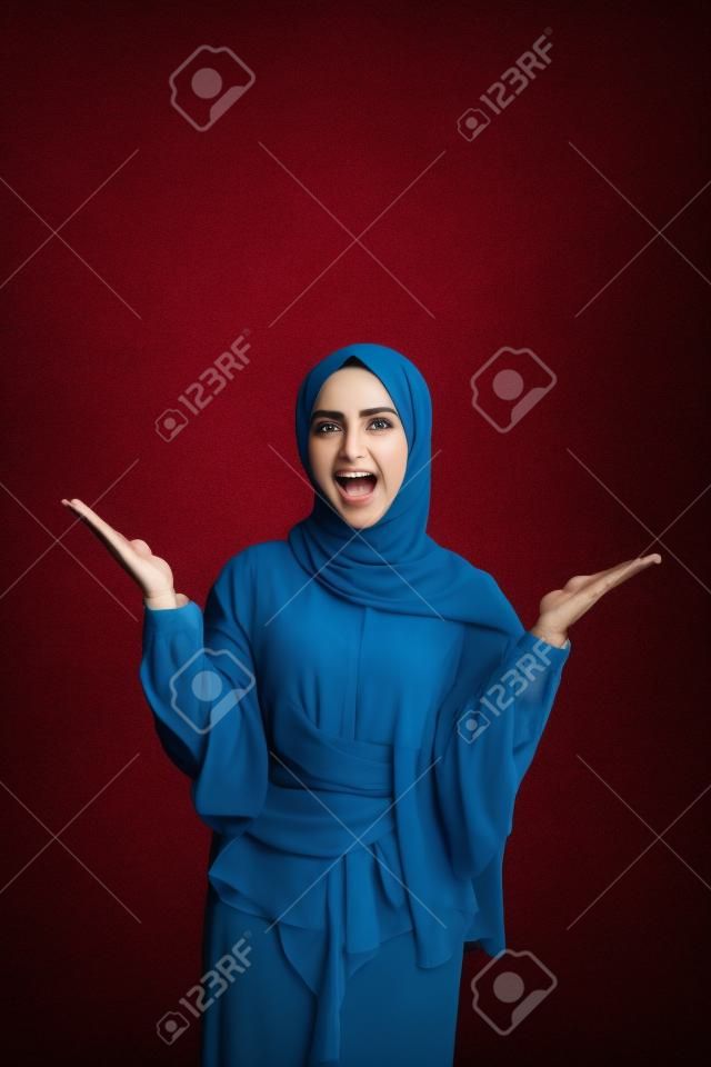mujer musulmana eufórica levantando el brazo en una foto de estudio