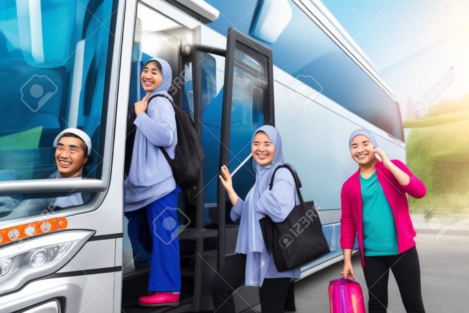 happy asian muslim passengers lined up in line to get on the bus