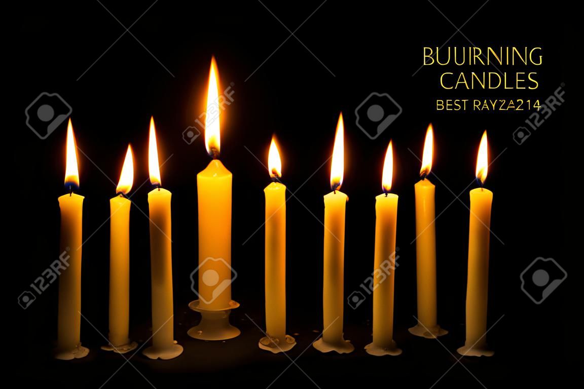 Six burning candles against black background