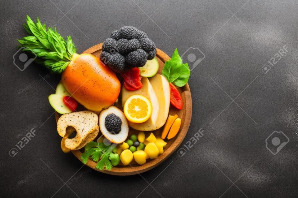 Coleção de alimentos saudáveis com anti-inflamatório e antioxidante em um prato de madeira, dieta do sistema imunológico com fibra, vitamina, ômega-3 e minerais, fundo cinza escuro, espaço de cópia, vista superior de cima