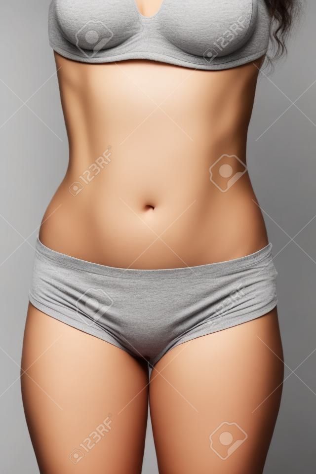 女性的腹部有舒展在灰色背景特寫鏡頭標記
