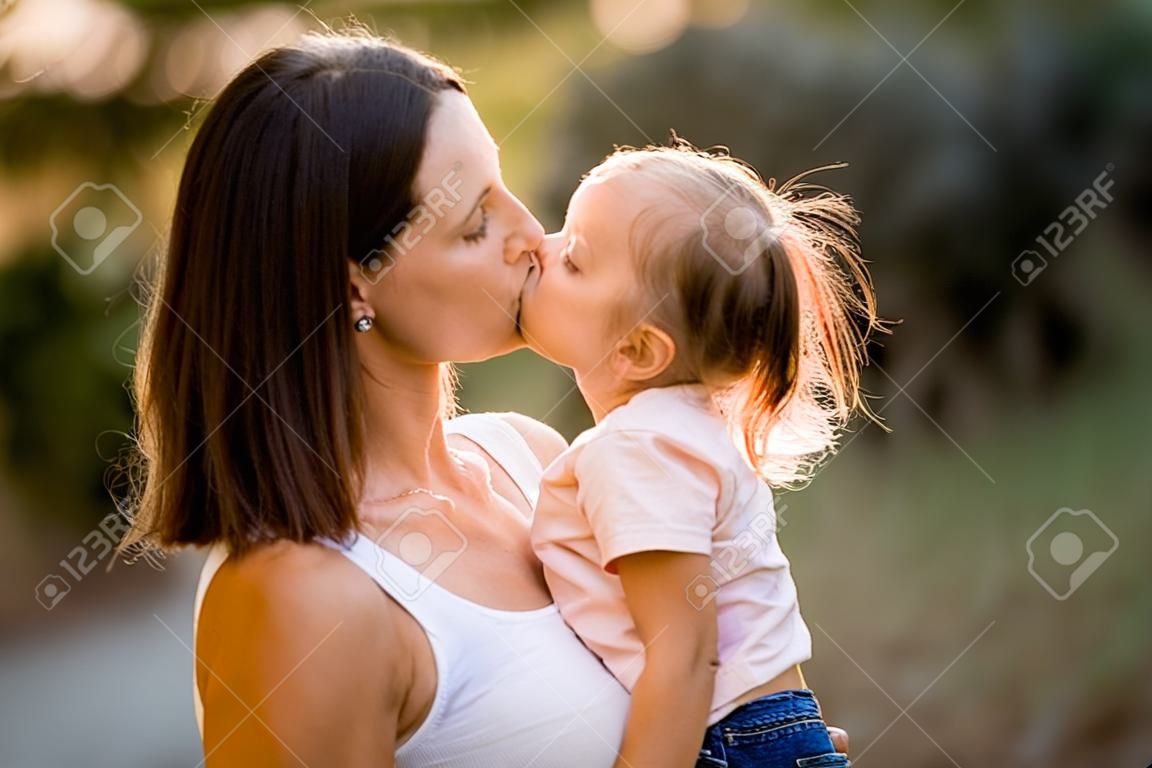Primer plano de mujer con niña en sus brazos que se están besando.