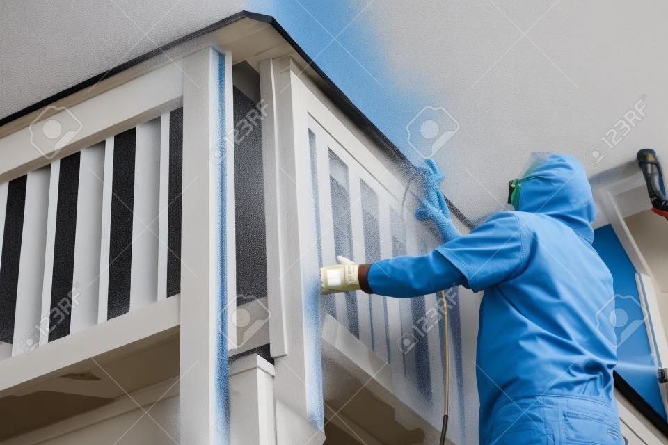 Huisschilder dragen gezichtsbescherming Spray Schilderen Een dek van een thuis.
