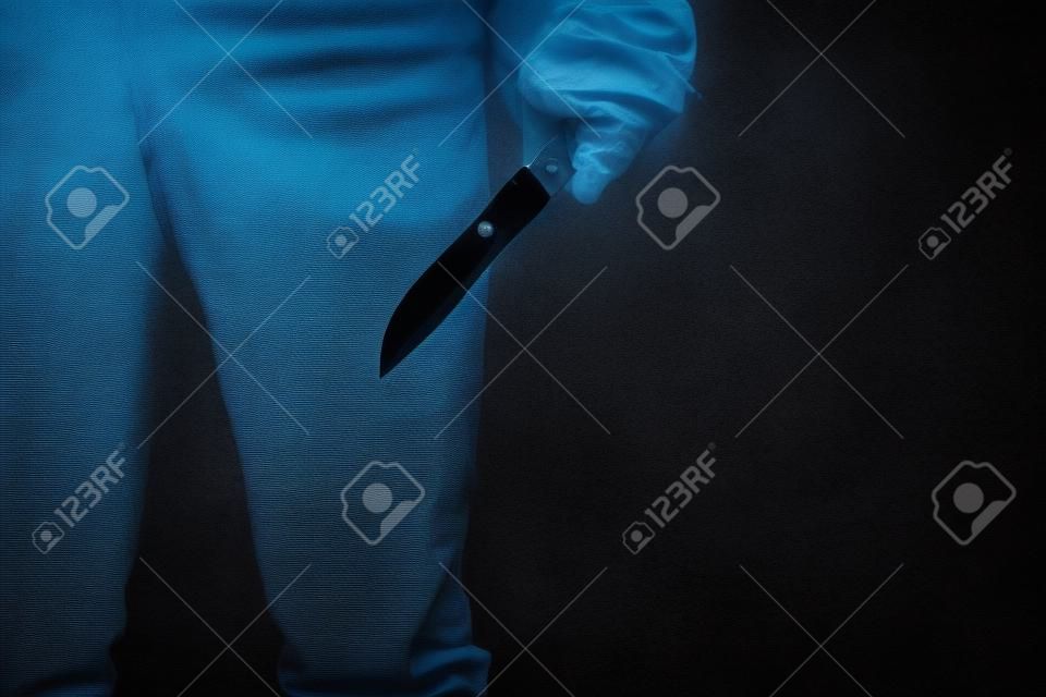Ręka seryjnego zabójcy z zakrwawionym nożem i czarnymi rękawiczkami
