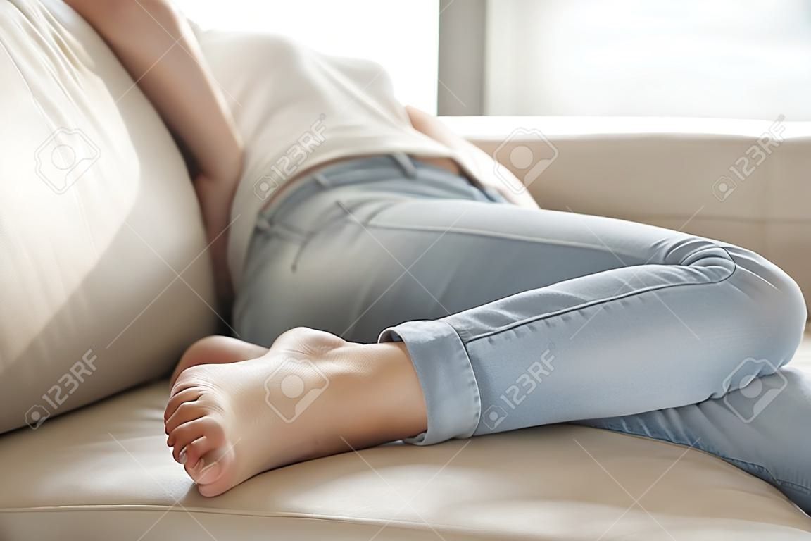 Tired woman in casual clothing sleeping on sofa, resting after hard day. Stressed or depressed lady lying on couch, frustrated because of problems in relations, suffering from loneliness or pain