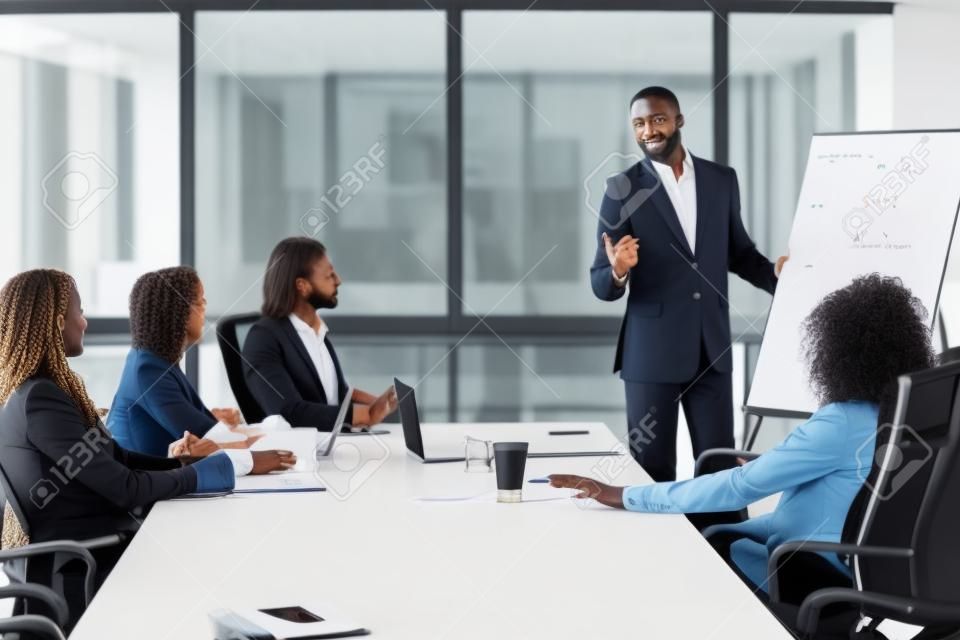 African businessman presenting new project to partners, black coach giving presentation to clients at conference meeting room, dark skinned team leader reporting about work result with whiteboard