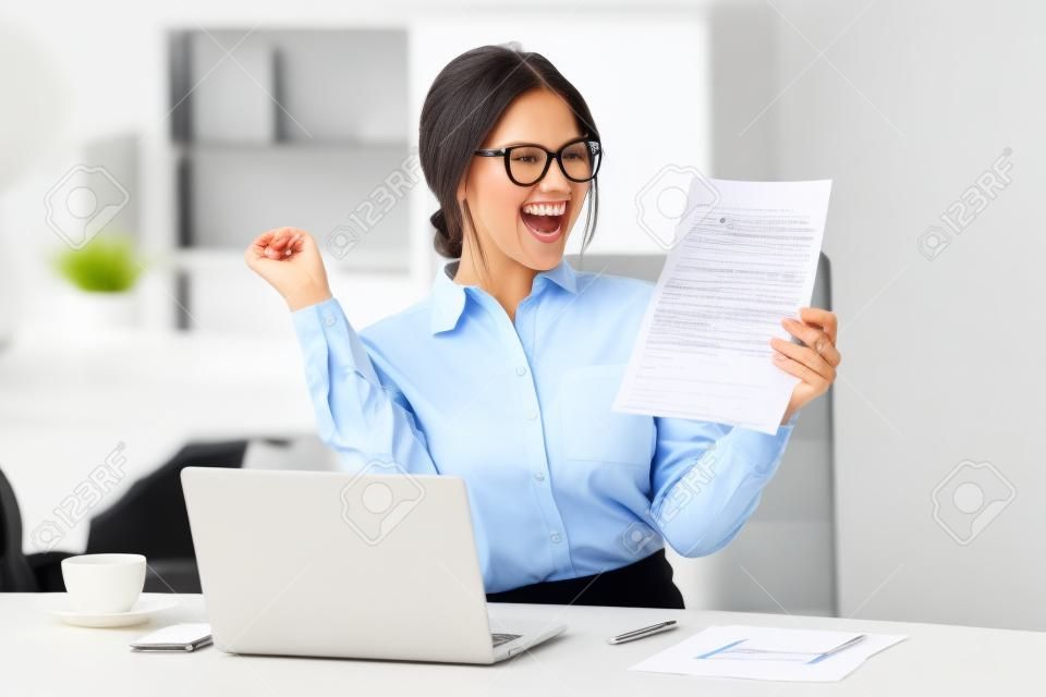 Excited satisfied businesswoman celebrating business success motivated by great financial work result in report, cheerful employee reading letter or notice with good news happy about job promotion