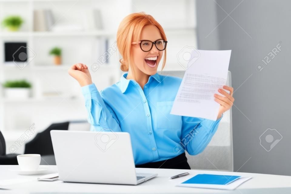 Excited satisfied businesswoman celebrating business success motivated by great financial work result in report, cheerful employee reading letter or notice with good news happy about job promotion